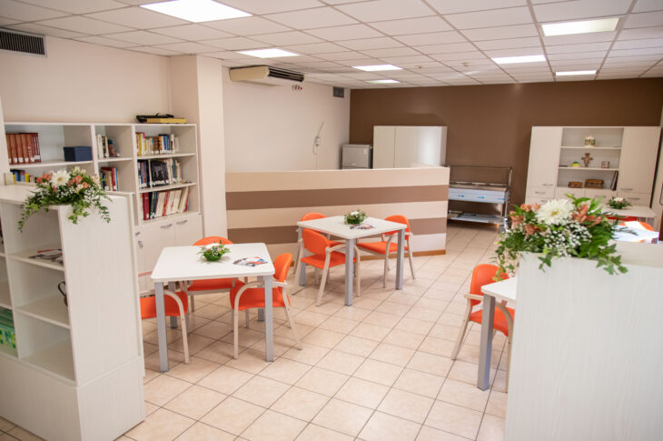 Spazio comune con tavoli, librerie e area dedicata alle attività degli ospiti.