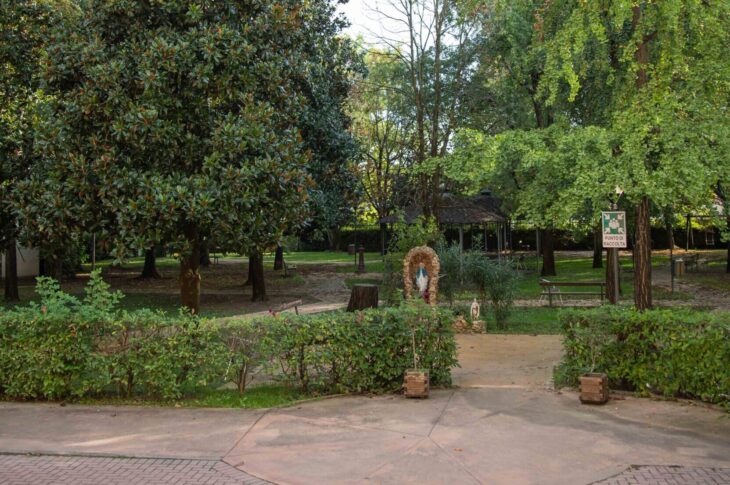 Giardino dell'ente con grandi alberi, sentieri pavimentati, panchine, gazebo e aree verdi accessibili.